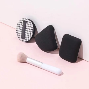 Poederdons set met pied-de-poule patroon en make-up kwast op roze achtergrond
