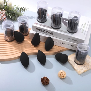 Set zwarte make-up sponsjes in een cilindrische doos op een minimalistische achtergrond