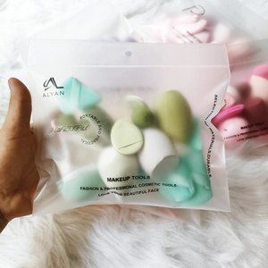 Multikleurige make-up sponsset in transparante zak op witte pluche achtergrond