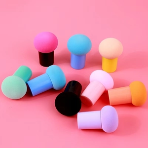 Éponges de maquillage tête de champignon avec poignées de couleurs sur fond rose