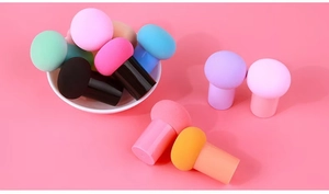 Colorful mushroom head makeup sponges with long handles in a white ceramic bowl