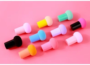 Flat lay of colorful mushroom head makeup sponges with handles on pink background