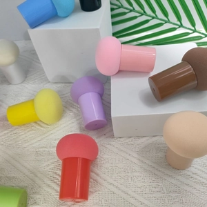 Macro shot of colorful mushroom makeup sponges with handles on a white textured background