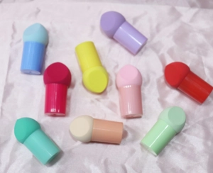Flat lay of colorful mushroom head makeup sponges with handles on pink silk background