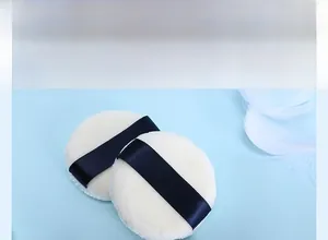 Detail of round double-sided velour powder puffs with navy blue ribbon and soft texture
