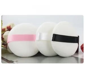 Detailed macro view of three white velvet powder puffs with colorful satin ribbons