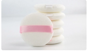 Macro shot of 5 round makeup puffs showing plush white texture and ribbon finger straps