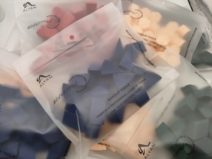 Macro view of assorted makeup sponge wedges in colorful bulk packaging bags