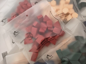 Macro detail of multi-shaped colorful makeup sponges in frosted ziplock packaging