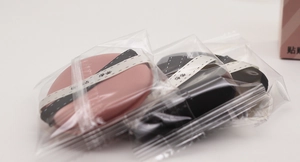 Detailed view of pink and black makeup puffs in individual hygienic travel packaging
