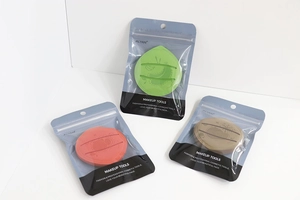 Three fruit-shaped makeup sponges in green, orange and tan colors in zipper packaging