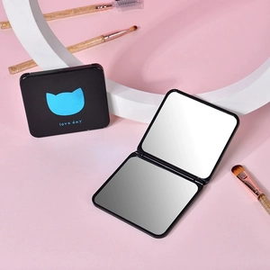 Miroir de maquillage pliable avec motif chat bleu et pinceaux sur fond rose doux
