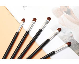 Detailansicht von fünf flachen Make-up-Pinseln mit schwarzen Griffen und Synthetikfaserborsten