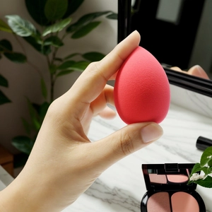 Macro shot of rose red teardrop makeup sponge showing fine texture and pointed tip detail