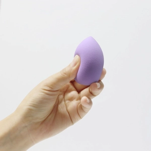 Close-up of a soft purple teardrop makeup sponge held between fingers on white background