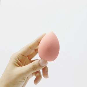 Macro shot of a pink teardrop makeup sponge showing soft texture and elastic material