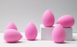 Macro shot of 6 bright pink teardrop makeup sponges on white geometric display stands