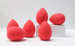 Detail of six high-density red teardrop makeup sponges displayed on white blocks