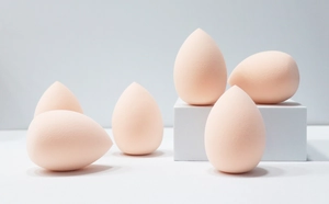 Close-up of teardrop makeup sponges in peach on modern geometric blocks for makeup