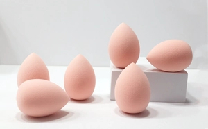 Macro view of peach water-drop makeup sponges on white blocks for makeup application
