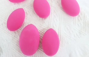 Detailed texture of rose red teardrop makeup sponges on elegant white lace background