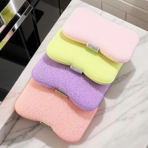 Close-up of four colorful honeycomb bath sponges with silver glitter bands on marble