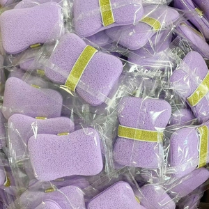 Macro shot of purple rectangle cleansing sponges with gold elastic bands in bulk packaging