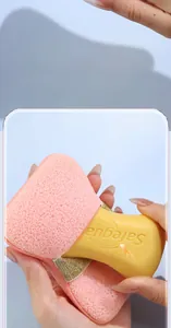 Close-up of pink cheese-shaped bath sponge producing rich lather with yellow soap
