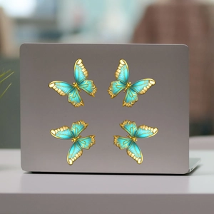 Close-up of four cyan and gold butterfly magnetic stickers on a laptop shell