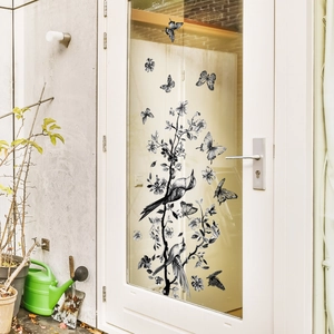 Ink style window decal with birds and flowers on a white glass door in a garden setting