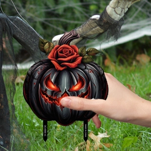Detail of Halloween pumpkin garden stake with red roses and glowing orange face design