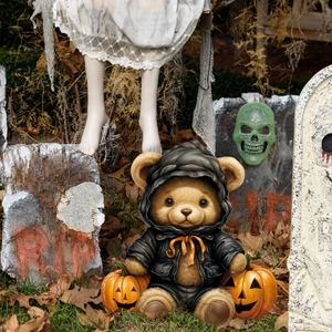 Halloween teddy bear in black leather hoodie with mini pumpkins in a spooky cemetery scene