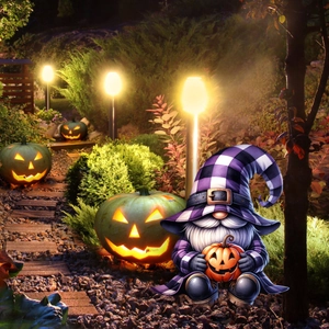 Close-up of Halloween gnome and glowing pumpkins illuminating a garden path at night