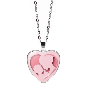 Detalle del colgante en forma de corazón con silueta de madre e hijo sobre fondo rosa