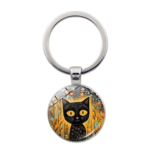 Detalle de llavero con colgante artístico de gato negro y fondo floral decorativo