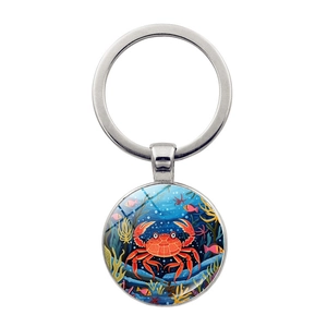 Macro shot of silver metal keychain with a cartoon crab and coral reef glass pendant