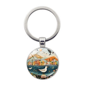 Detailed macro view of silver turtle keychain featuring artistic seaside town landscape art