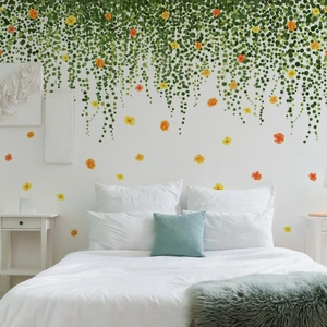 Detail of green vine wall stickers with yellow flowers on a bedroom wall above a bed