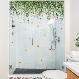 Detail of hanging green vine wall stickers with flowers on a glass shower door
