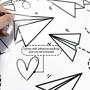 Detail showing self-adhesive paper plane wall sticker being peeled off without residue