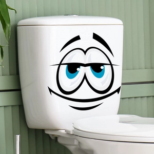 Funny smiling cartoon face sticker on white ceramic toilet tank in a modern bathroom