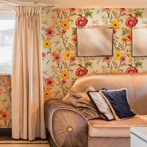 Pastoral floral wallpaper with red and orange flowers and birds in a living room scene