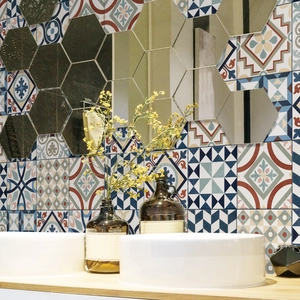 Close-up of hexagonal mirror wall stickers in a bathroom above a tiled washbasin