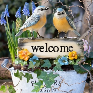 Detail of creative welcome bird garden stake with resin birds and vintage flower bucket
