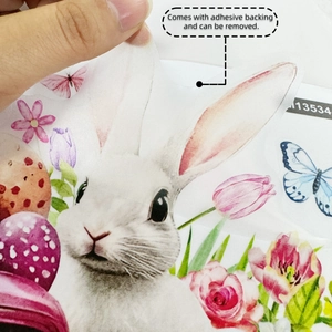 Detail showing hand peeling self-adhesive Easter bunny and tulip stickers for bathroom decor