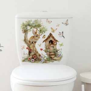 Detailed watercolor rabbit and garden treehouse sticker on a white ceramic surface