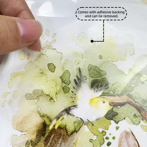Detail of yellow bird and green plant wall decal being peeled by hand showing adhesive
