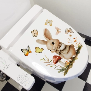 Detailed watercolor bunny and butterfly wall stickers on a white toilet lid surface