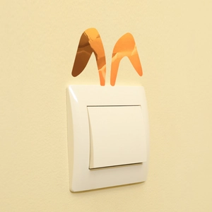 Detailed close-up of golden metallic rabbit ear wall stickers applied on a light switch