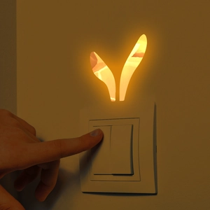 Detail of a golden mirror rabbit ear wall sticker being applied above a light switch